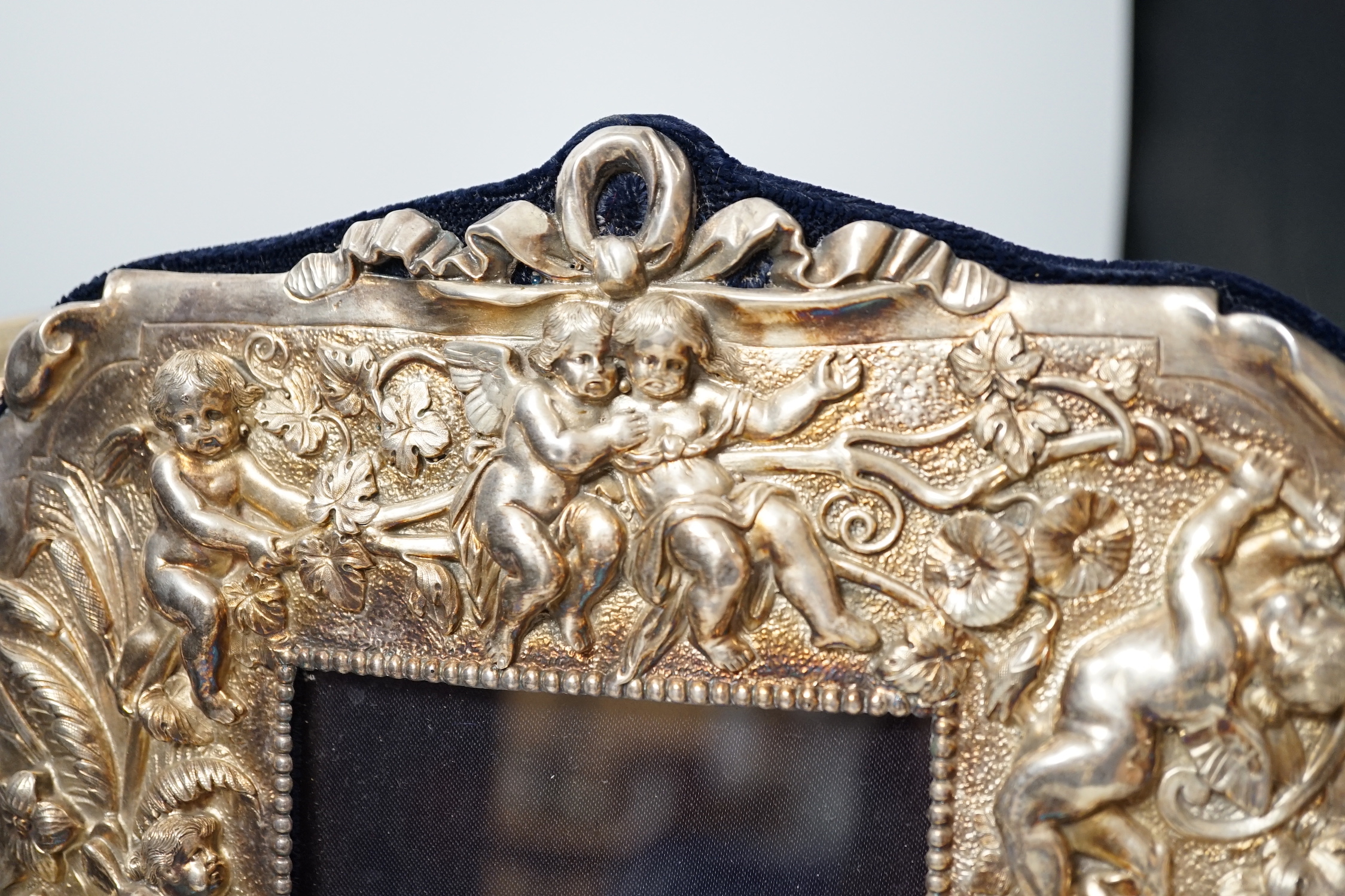 Three assorted modern silver mounted photograph frames, the largest decorated with putti amongst flowers, 27.5cm.